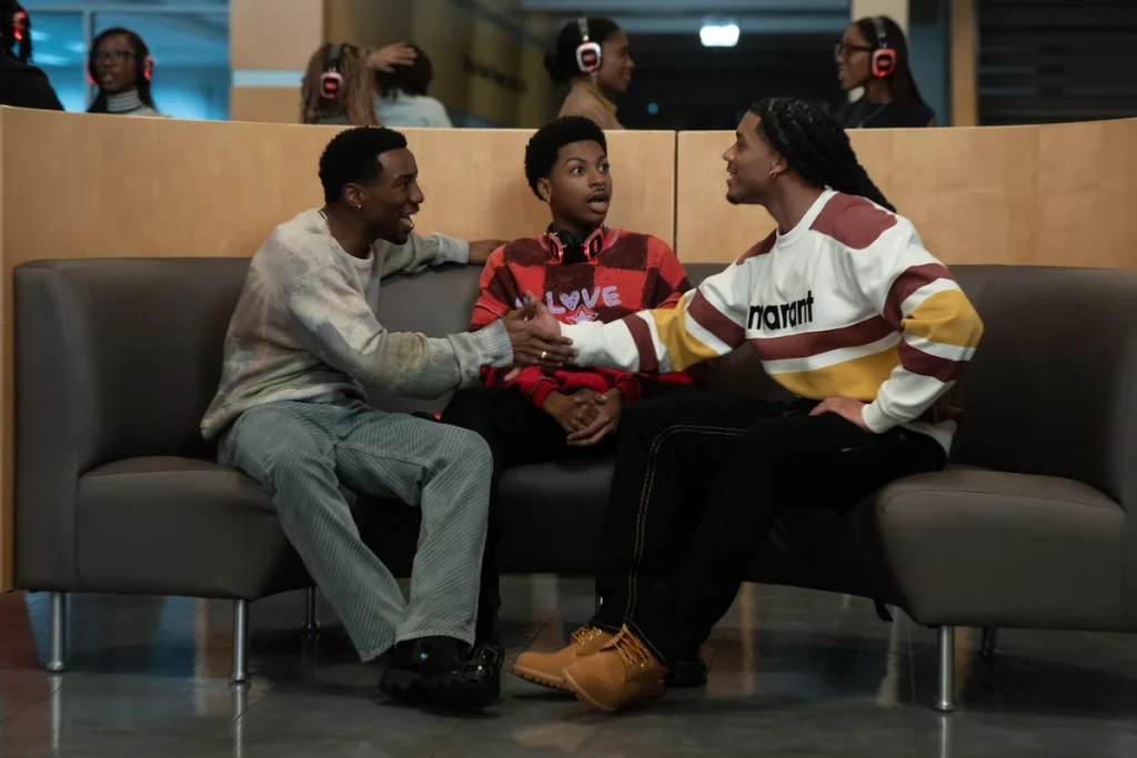 Three students share a couch while two shake hands across the middle student in A Different World