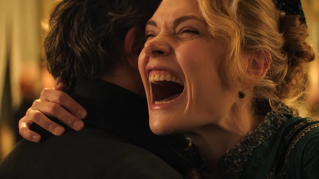 A blonde woman in period dress laughs while embracing someone in The Doll