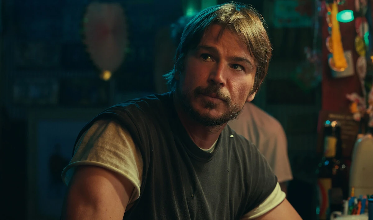 Calvin Penney sits at a bar, looking to his left in Below.
