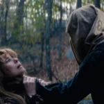 Crystal Lake Ending: Why Pamela Laughs After Jason Attacks Her Pamela looks up at a sack-masked Jason as he holds her against a tree.