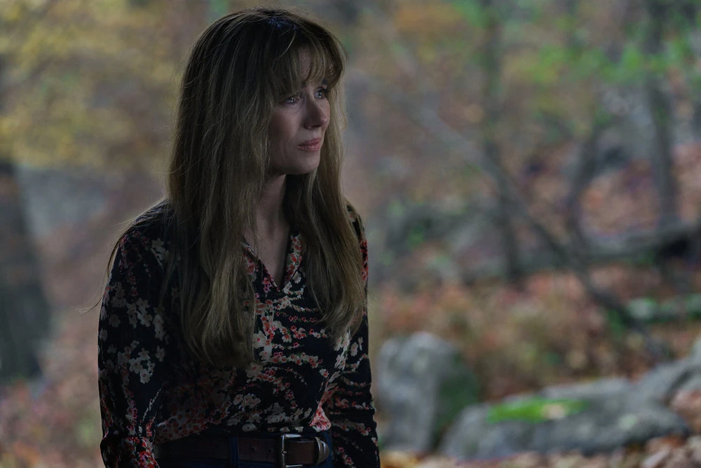 Pamela stands outdoors in a dark floral blouse.