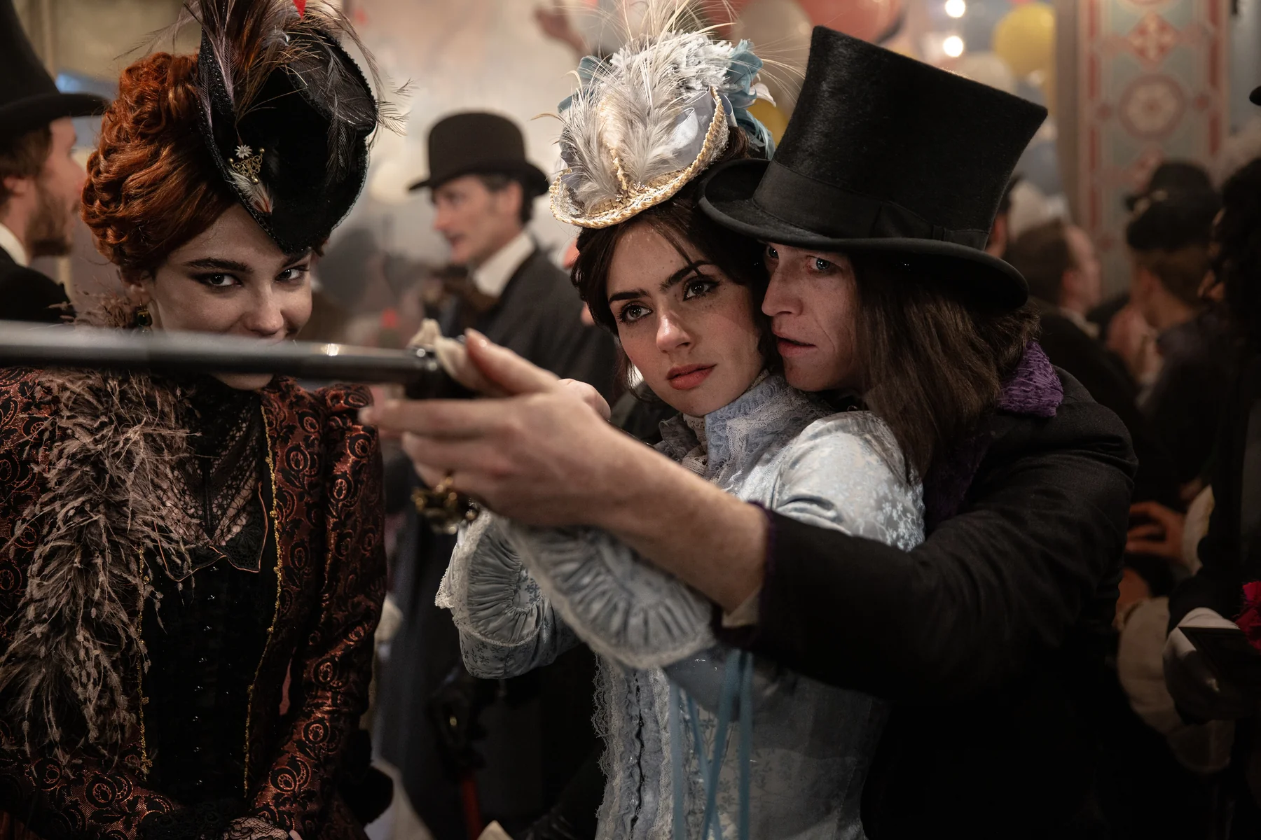 A man in a top hat guides a woman's rifle while another woman watches in Dracula.