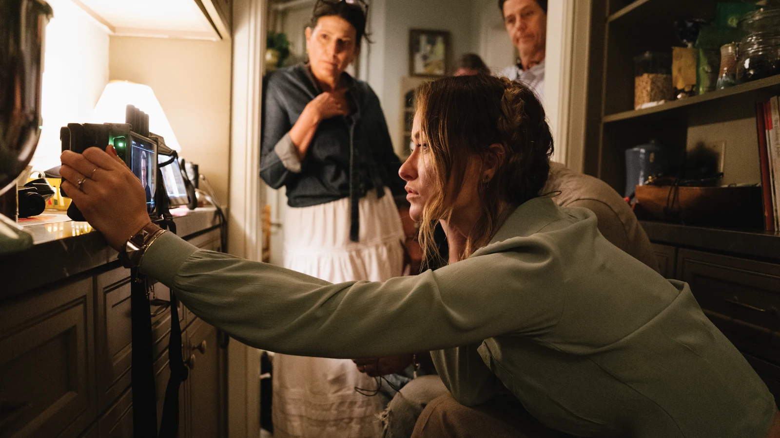 Olivia Wilde leans toward a monitor on the set of The Invite.