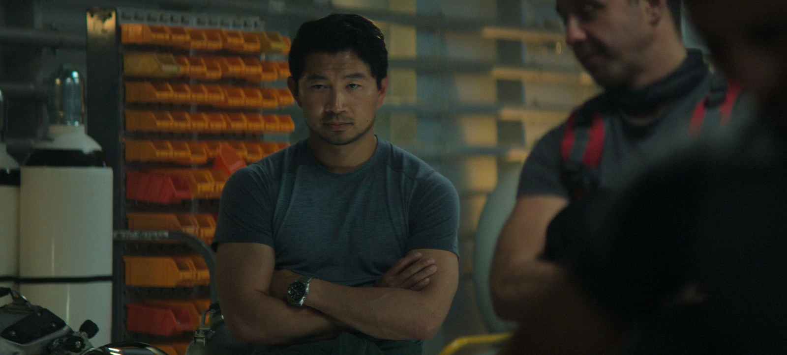 Dave Yuasa stands with his arms folded beside orange equipment in Last Breath.