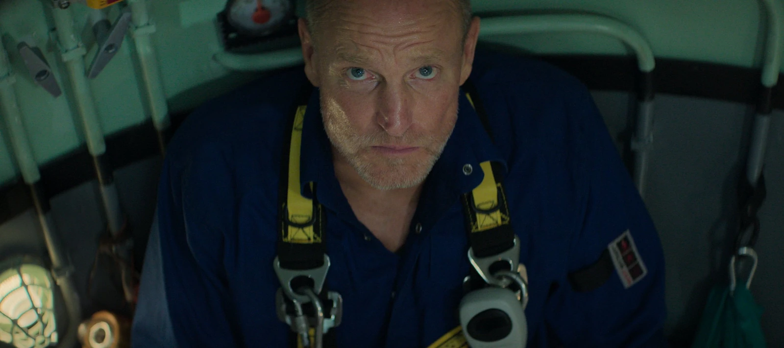 Duncan Allcock looks upward while wearing a blue work suit and yellow harness in Last Breath.