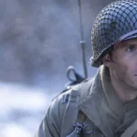 John Castle (Scott Eastwood) wears a netted helmet with a radio antenna behind his shoulder in Lucky Strike.