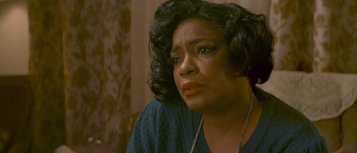 Mrs. Caldwell (Aunjanue Ellis-Taylor) sits in an armchair beside patterned curtains in Lucky Strike.