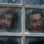 In Mayday, the Top Gun Fan Has to Save the Pilot Nikolai and Troy peer through a frosted window in Mayday.