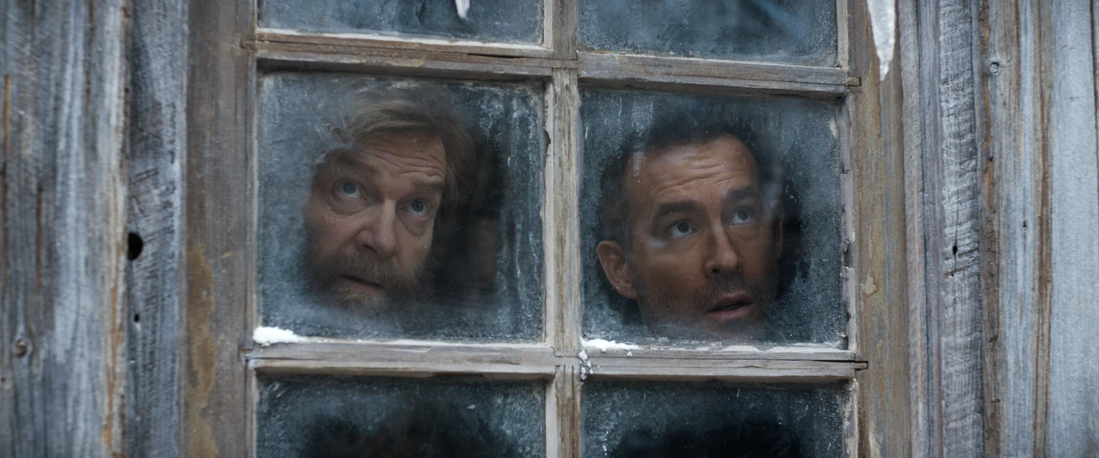 Nikolai and Troy peer through a frosted window in Mayday.