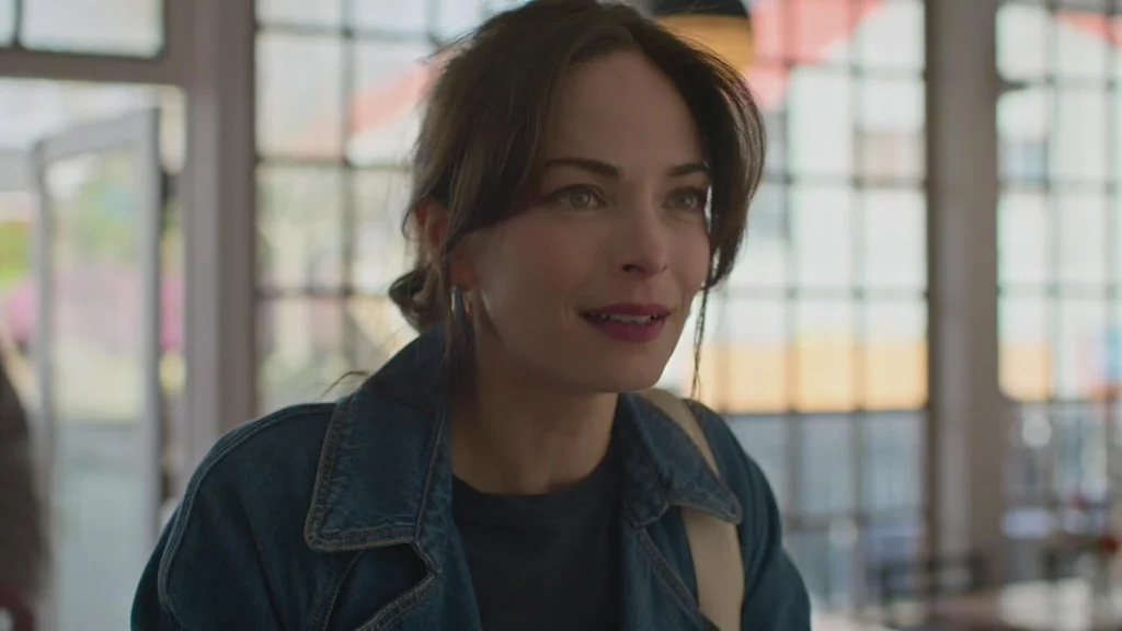 A woman in a denim jacket beside a window in Murder in a Small Town