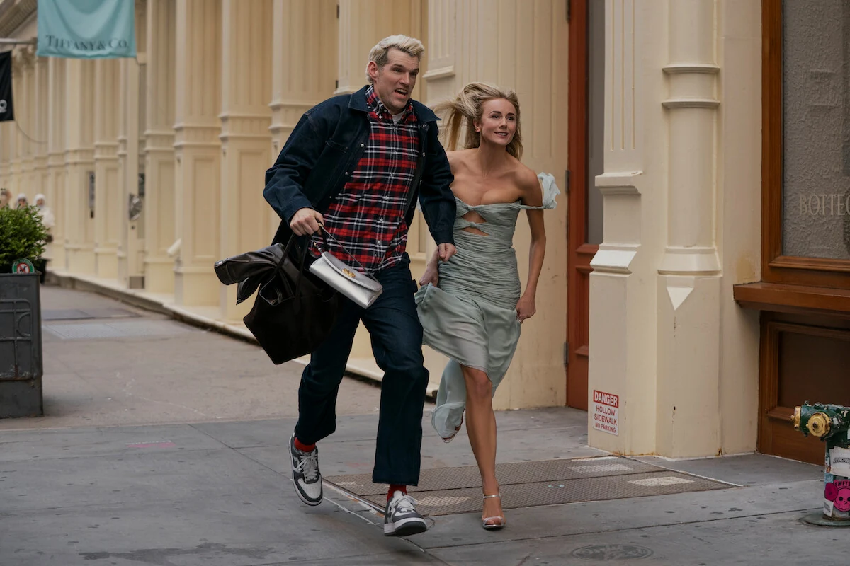 Sasha and Morgan run together along a sidewalk beside storefronts.