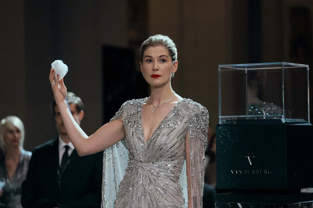 Veronika holds up a diamond beside a glass display case.