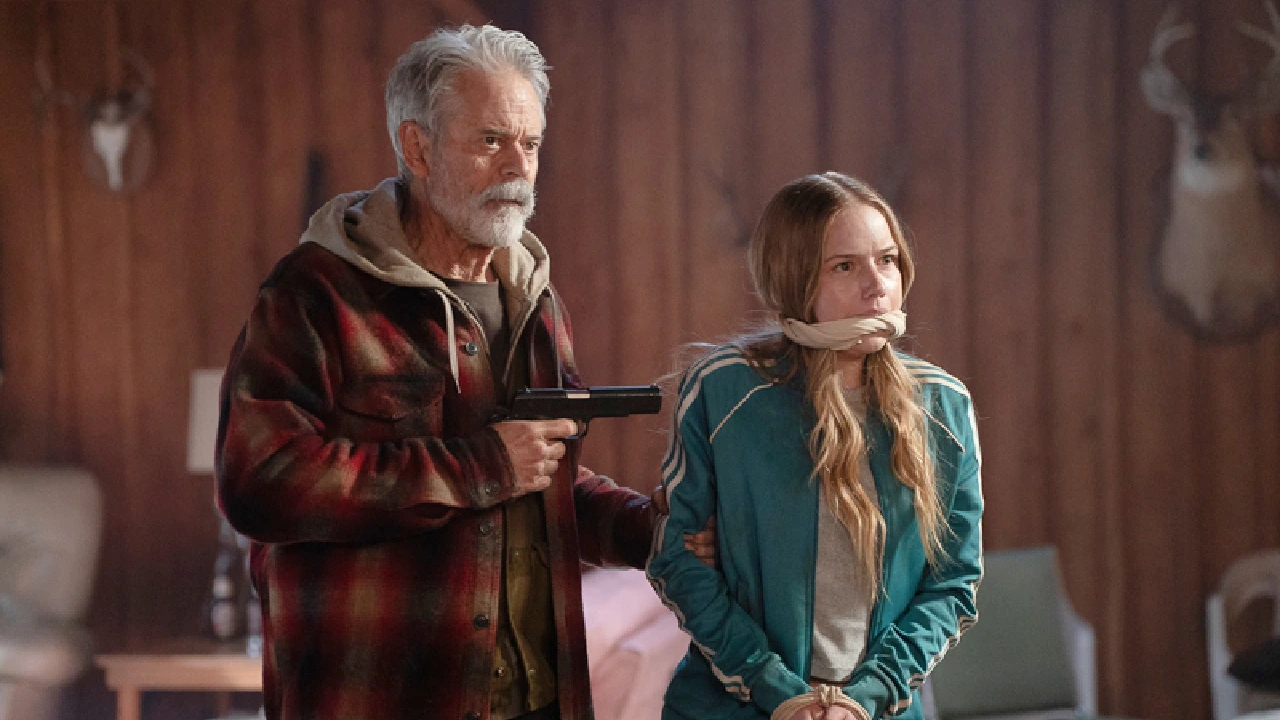 Stanley holds a handgun beside a bound and gagged Alex in One Mile.