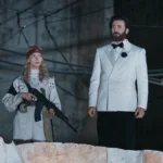 Joan holds a rifle beside Mike Tyler in a white dinner jacket in Sacrifice