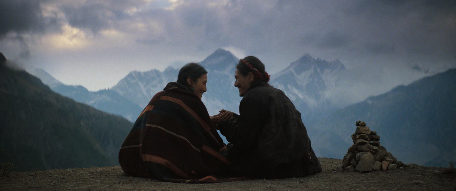 Dawa and a younger Tenzing sitting together with mountains behind them