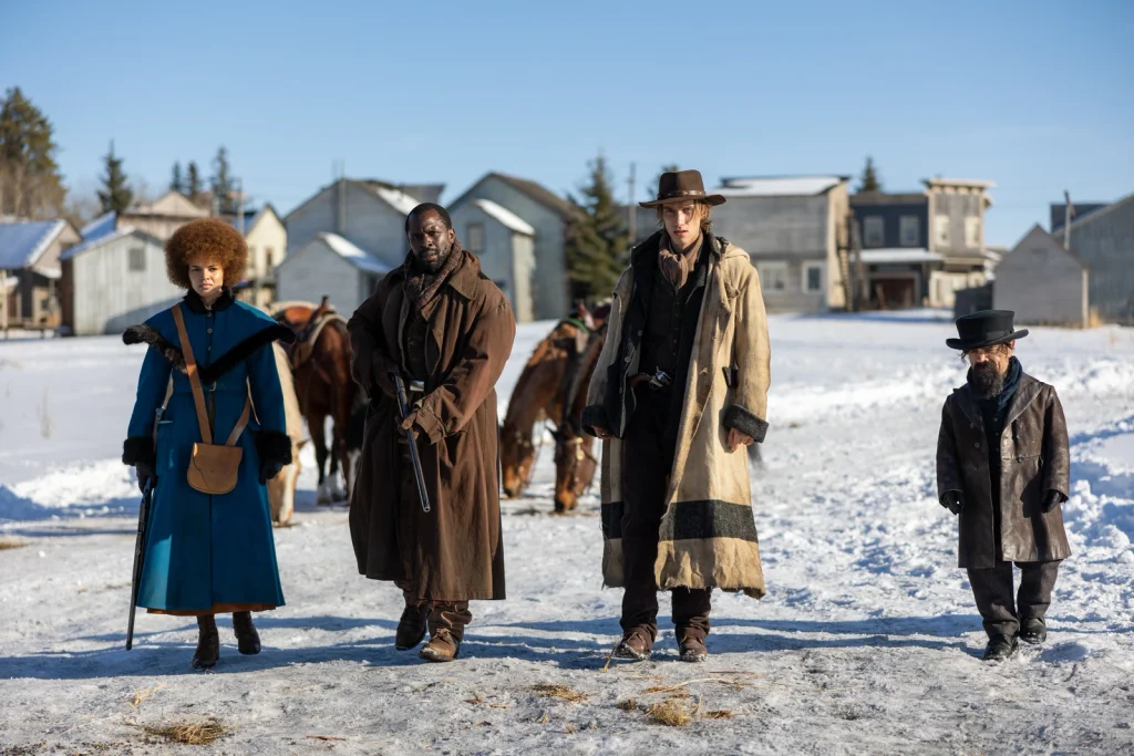 Four travelers walk along a snowy street with horses behind them in The Thicket