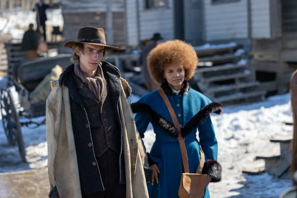 A young man in a brimmed hat stands beside a woman in a blue coat in The Thicket