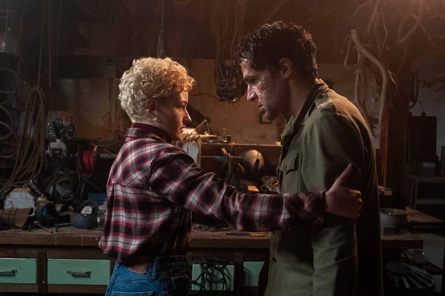 Charlotte holds Blake’s upper arm as they face each other beside a workbench in Wolf Man.