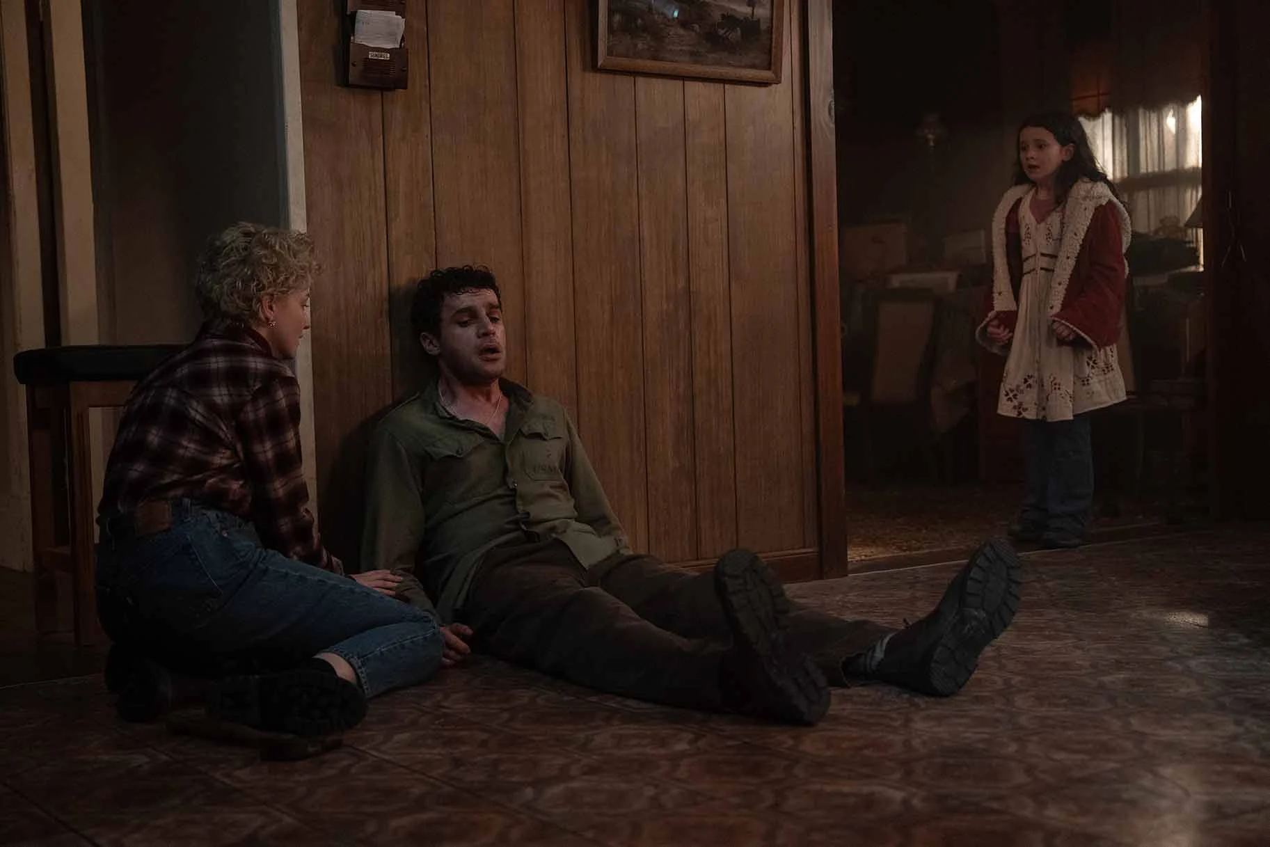 Charlotte sits beside Blake against a wood-paneled wall while Ginger stands in the doorway in Wolf Man.